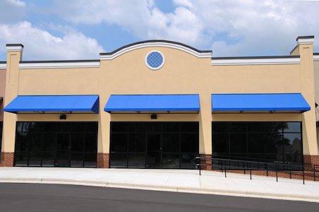 Blue commercial awnings installed over the doors of a business