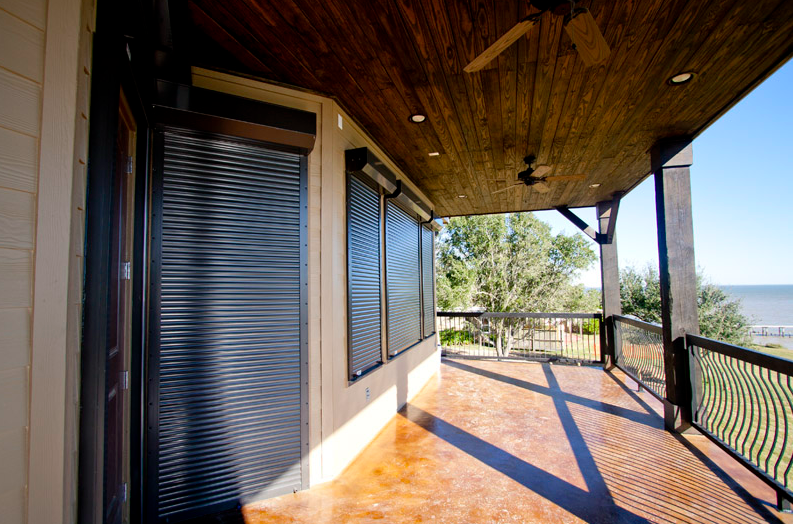 Front Porch Of A Beach Home With Black, Rollac Hurricane Shutters On the Windows