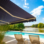 Two Lawn Chairs Next to a Swimming Pool with Rollac Retractable Awning Fully Open