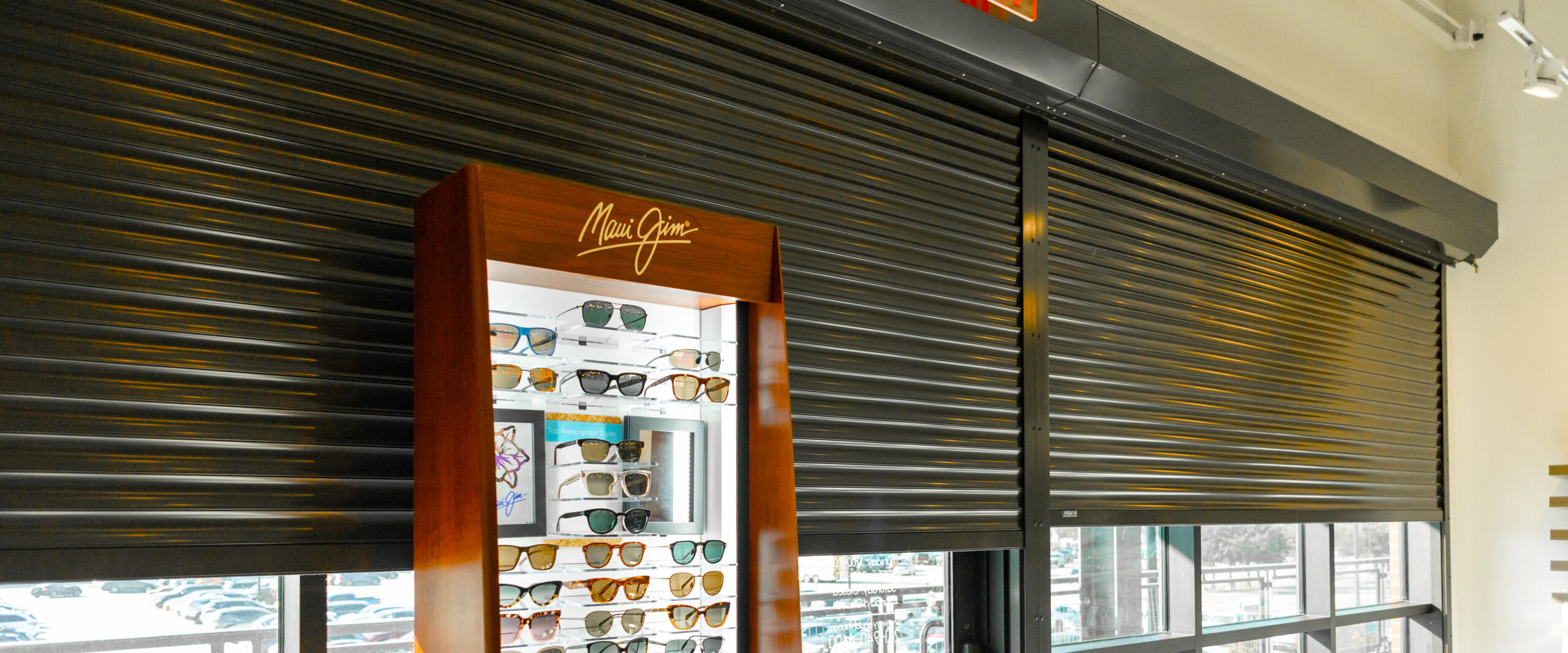 Close Up of Storefront with Security Roller Shutters Installed and a Stand of Sunglasses