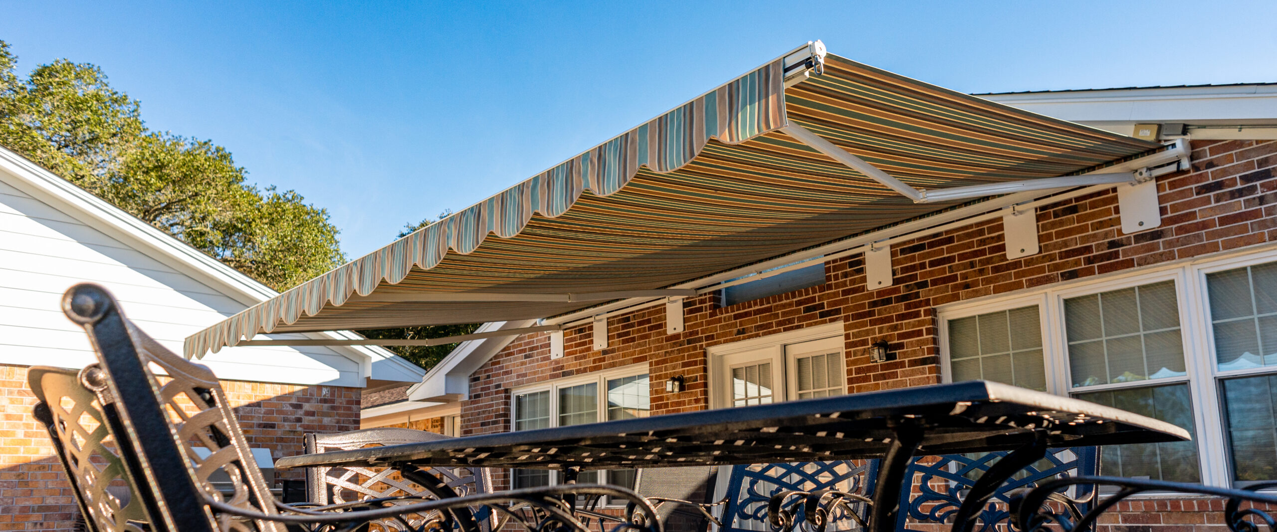 Large Retractable Awning with Green, Orange, and Brown Stripes