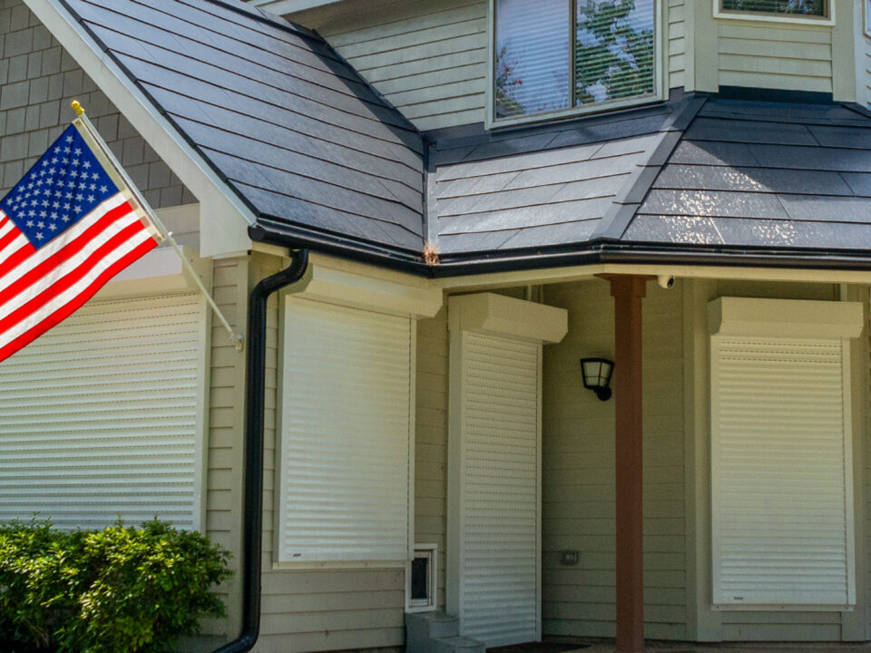 Exterior View of a House with the U.S. Flag and Rolling Shutters Installed at Windows and Doors