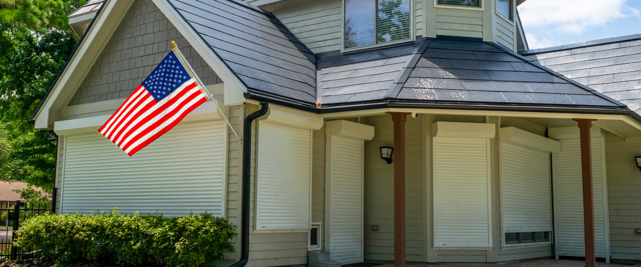 Exterior View of a House with the U.S. Flag and Rolling Shutters Installed at Windows and Doors