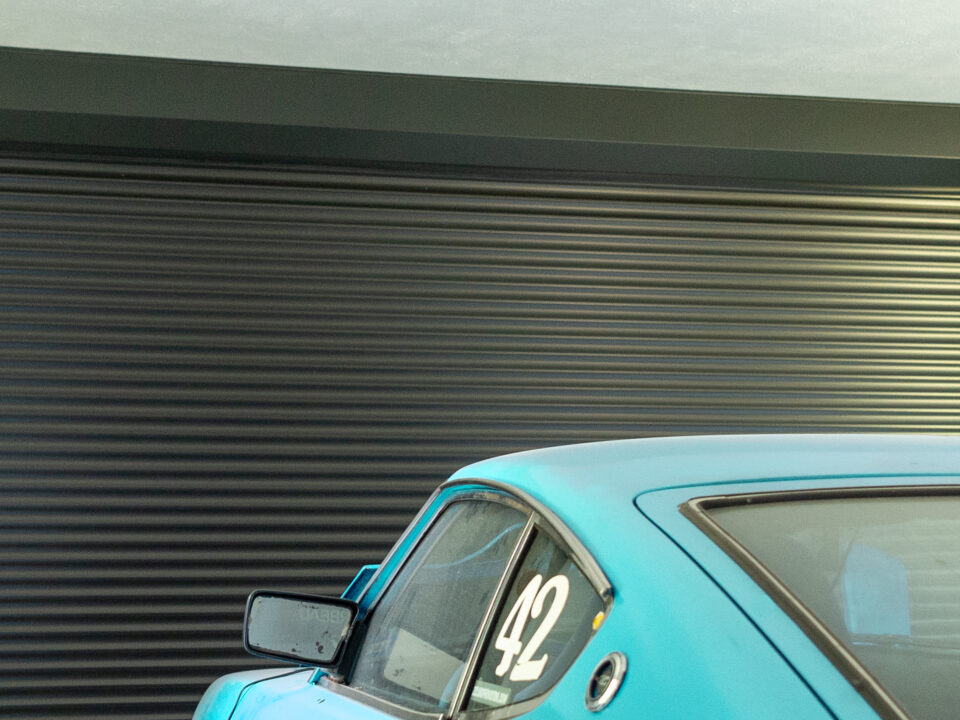 Garage Door With Security Roller Shutters and a Blue Car Parked Outside