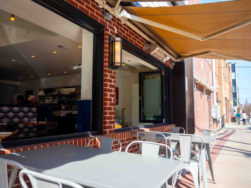 Large retractable awning opened over tables of restaurant on the sidewalk