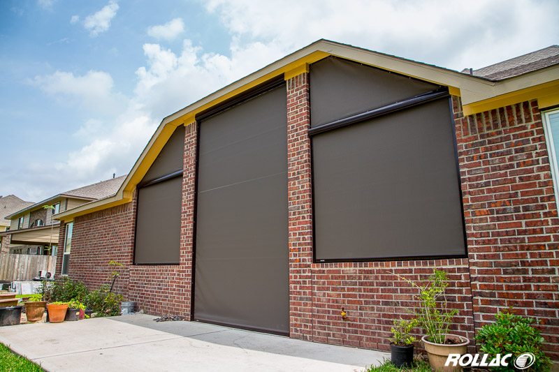 Exterior view of a brick house with large window shades fully extended for sun protection and privacy